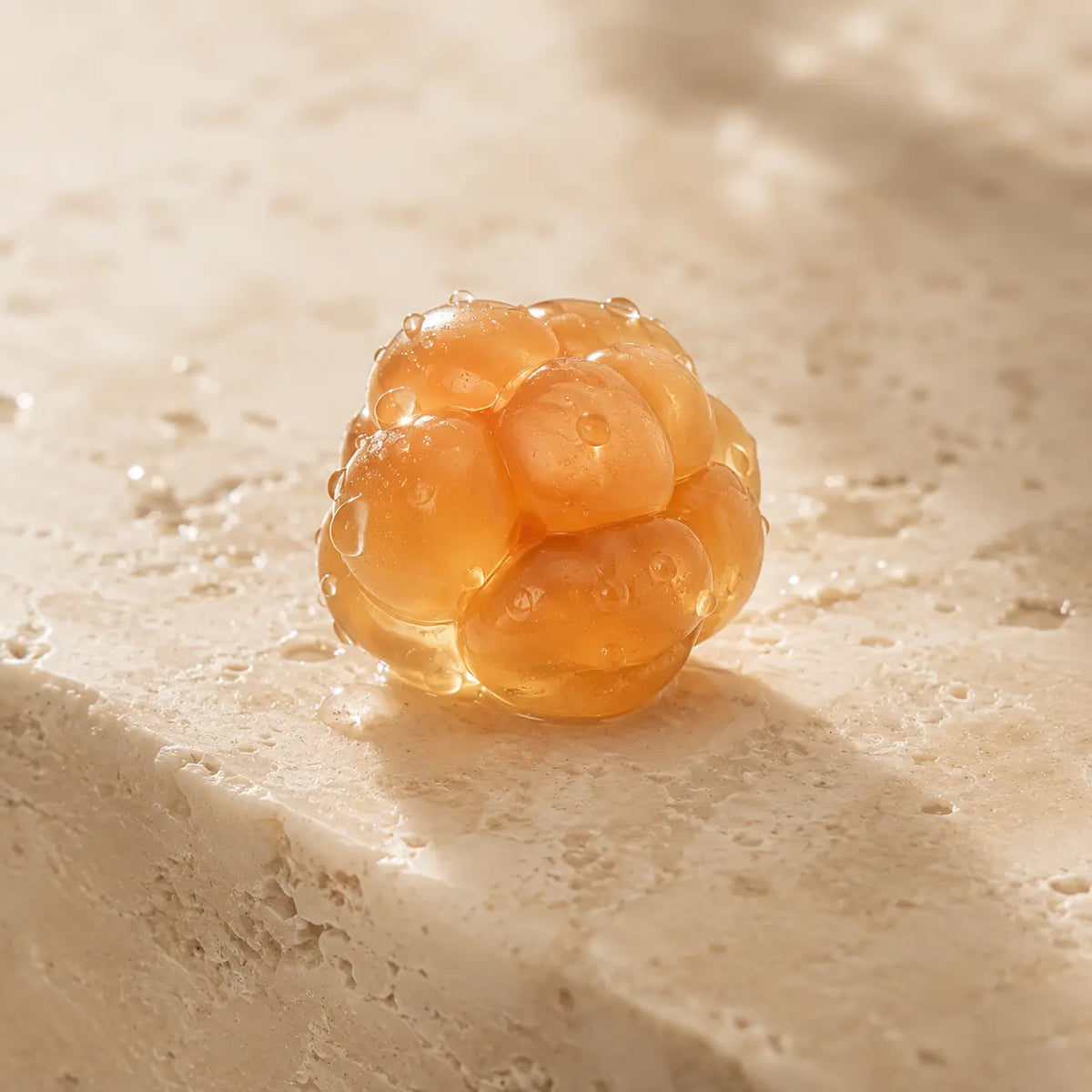Artistic macro photograph of a Nordic cloudberry with delicate water droplets symbolizing antioxidant-rich botanical skincare.