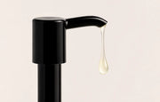 SÖMA GLOW Post-Sculpt Glow Oil texture flowing from a dispenser. Lightweight golden body oil designed for post-studio skincare and women in motion