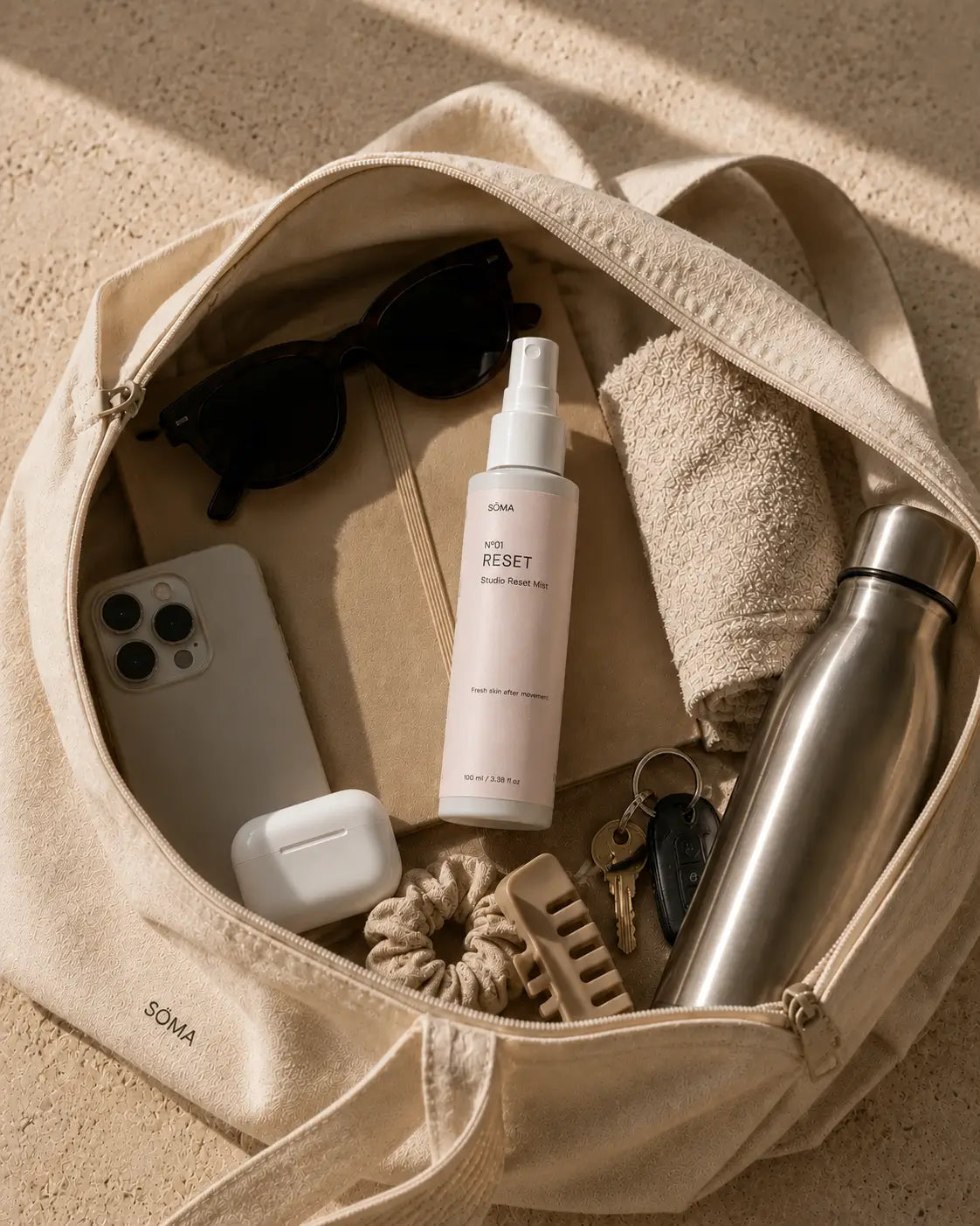 SÖMA No. 01 Reset Studio Mist inside a minimalist studio tote with everyday essentials including a towel, water bottle, sunglasses and hair accessories.